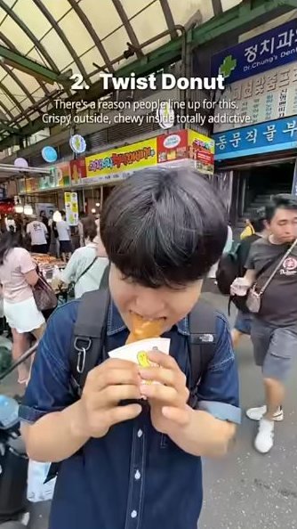 Bae eating a twisted doughnut in the covered market walkway.