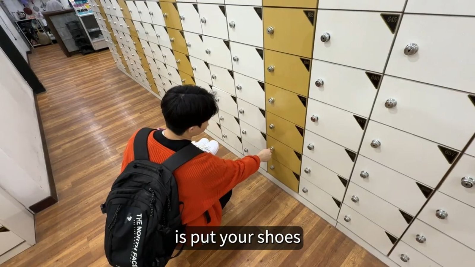 Bae placing his shoes in a small numbered shoe locker