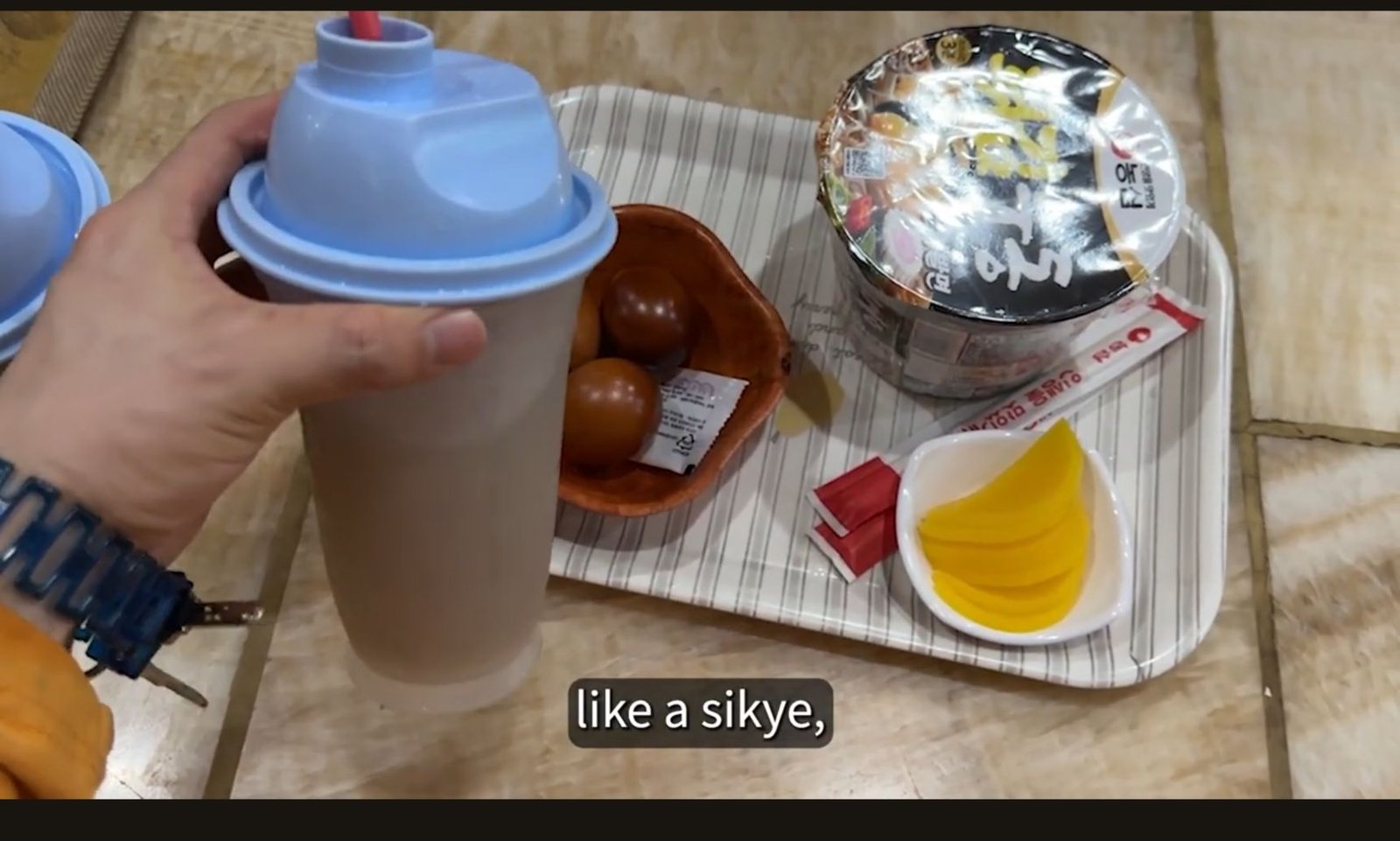 A drink cup, roasted eggs and instant noodles on a tray in Bae’s jjimjilbang visit